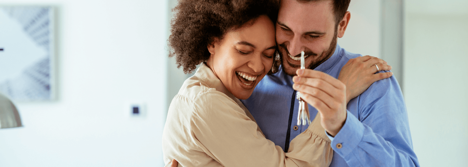 Happy couple smiling and celebrating getting the keys to their new home - is now a good time to buy a house